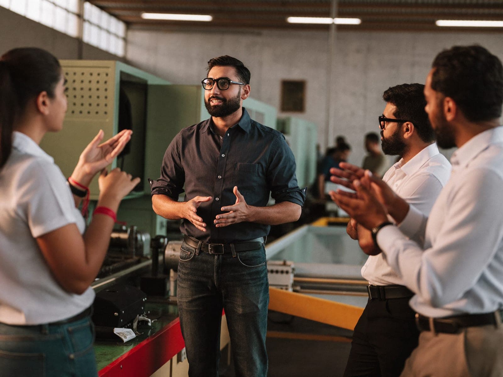 A team lead talking with technicians beside a production line